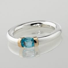 This delightfully hand crafted Sterling silver tension ring makes the ideal choice as a birthstone gift with a mediterranean sea Blue Topaz representing those born in November. The gemstone has a solid gold detail on each shoulder, with the contrasting precious metals enhancing beautifully with the light bright blue of the topaz gemstone. Tension held stones allow the light to reflect the colours without interference from the metalwork. We have been hand making these rings for the last 25 years, Luxury Anniversary Topaz Ring With Bezel Setting, Modern Topaz Birthstone Ring As Gift, Modern Topaz Ring As Birthstone Gift, Blue Topaz Tension Setting Ring Gift, Topaz Ring With Tension Setting Gift, Blue Topaz Rings With Tension Setting For Gift, Gift Topaz Ring With Tension Setting, Tension Ring, Sterling Silver Jewelry Rings