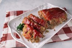 two slices of meatloaf on a white plate with a red and white checkered tablecloth