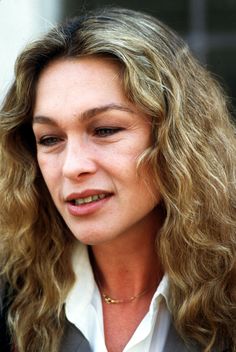 a close up of a person wearing a suit and tie holding a cell phone to her ear