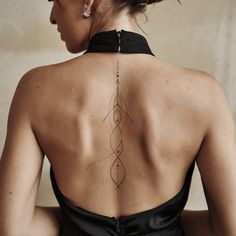 the back of a woman's dress with an intricate tattoo on her upper back