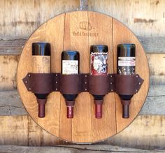 a wine rack with four bottles on it and leather straps hanging from the wall in front of wooden planks