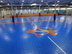 an indoor basketball court with blue and orange flooring