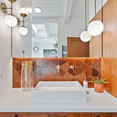 a bathroom sink sitting under a mirror next to a wooden cabinet with lights on it