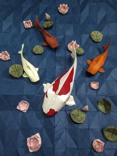 some origami flowers and leaves on a blue surface