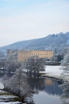 a large building sitting on top of a snow covered hill next to a body of water