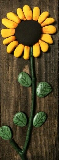 a sunflower made out of clay sitting on top of a wooden table