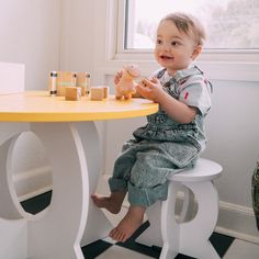 a toddler sitting at a table playing with wooden blocks and a piggy bank