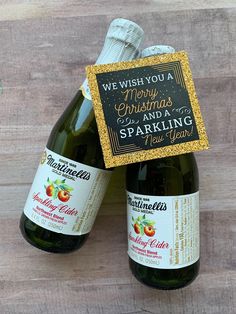 two bottles of sparkling cider wine with a sign that says we wish you a merry christmas