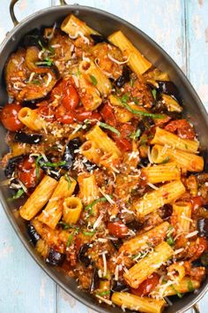 a skillet filled with pasta and sauce on top of a blue wooden table next to a