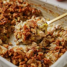 a casserole dish with meat and vegetables being scooped from the casserole