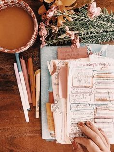 a person's hand is writing on a notebook surrounded by flowers and other crafting supplies