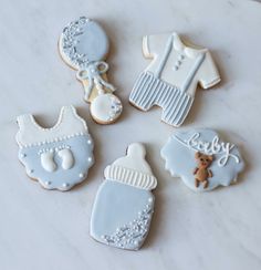 some cookies that are shaped like baby clothes and onesuits on a counter top