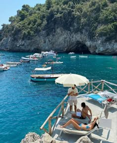 two people are sitting on a boat in the water with an umbrella over their head