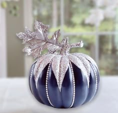 a blue pumpkin with silver leaves on it's top sitting in front of a window