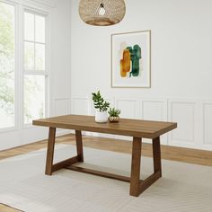 a wooden table sitting on top of a white rug next to a potted plant