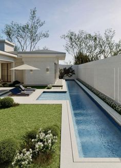 an outdoor swimming pool with lounge chairs and umbrellas next to the side of a house