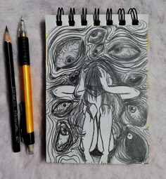 a drawing on a notebook next to two pencils