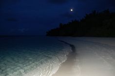 there is a path going through the water to the beach at night with moon in background