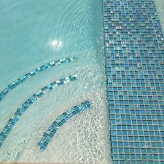 an aerial view of a swimming pool with blue tiles on the floor and in the water