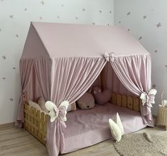 a child's bed with pink sheets and curtains on the top, next to a teddy bear