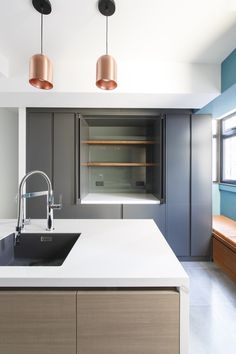 a kitchen with an island sink and two copper lights hanging from the ceiling over it