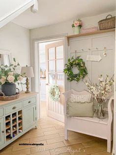 a white bench sitting in the middle of a living room next to a doorway with flowers on it