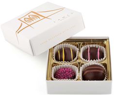 four chocolates in a white box with pink and yellow sprinkles