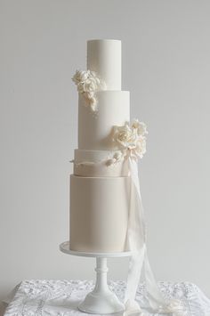 a three tiered white wedding cake with flowers on top