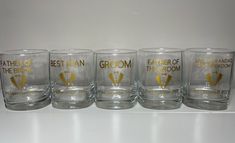 six shot glasses sitting on top of a white counter next to each other with the words, father of the bride and groom written on them