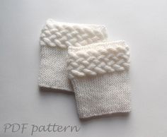 two white knitted mittens sitting next to each other on top of a table