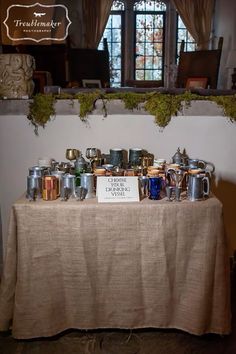 a table topped with lots of cups next to a window