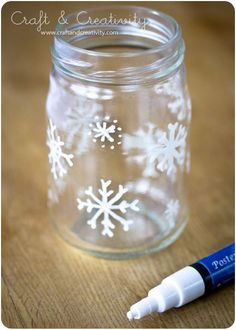 a glass jar with white snowflakes on it and a marker next to it