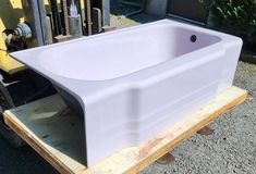 a large white bath tub sitting on top of a wooden pallet