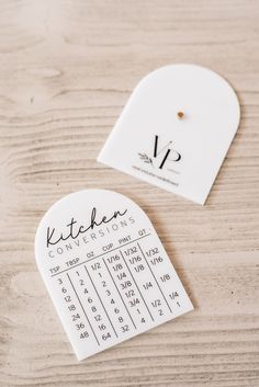 a pair of scissors sitting on top of a wooden table next to a white tag