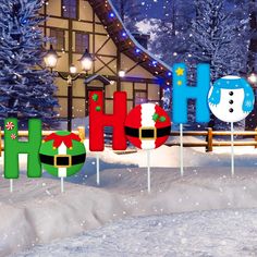 the word holiday spelled out in front of a snow covered house and christmas trees with lights