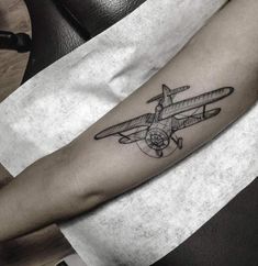 a small airplane tattoo on the arm