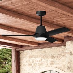 a black ceiling fan mounted on the side of a brick wall next to a clock