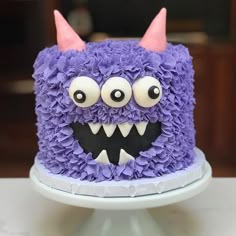 a cake decorated with purple and white icing has a monster's face on it