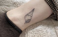 a woman's arm with a tattoo on it that has a seashell on it