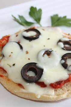 an open face pizza with cheese and black olives on the top is sitting on a white plate