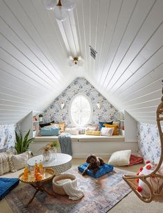 an attic bedroom with white walls and blue floral wallpaper on the ceiling is furnished with furniture