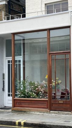 an open window on the side of a building with potted plants in front of it