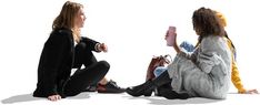 two women sitting on the ground talking to each other