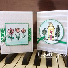 two handmade cards with flowers on them sitting next to each other in front of a piano