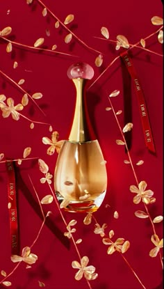 a gold vase with flowers and ribbons hanging from it's side on a red wall