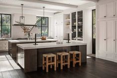 a kitchen with white cabinets and wooden stools next to an island in the middle