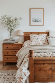 a wooden bed sitting next to a white wall with flowers on the headboard and foot board