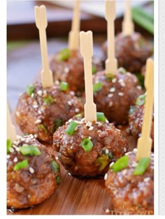 some meatballs with toothpicks in them sitting on a wooden board and ready to be eaten