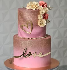 a pink and gold wedding cake with flowers on top