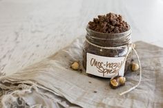 a jar filled with nuts sitting on top of a cloth covered table next to a napkin